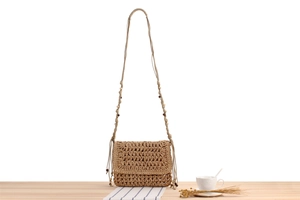 Detailed close-up of khaki woven crossbody bag with decorative wooden beads and straw texture