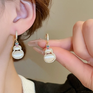 Macro detail of cat eye stone hulu earrings with zircon inlays and gold plating