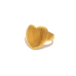 Golden heart ring with striped texture on a white background with soft shadows