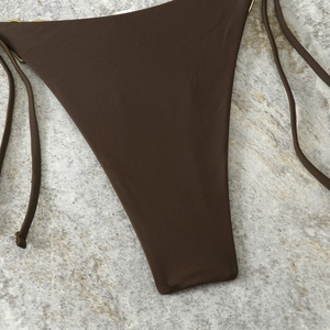 Detail of dark brown bikini bottoms with gold ring accents and side tie strings