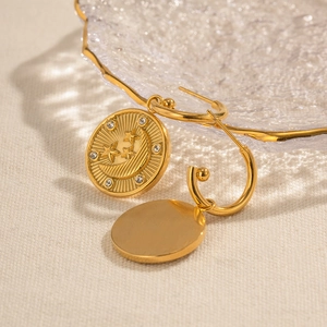Detailed view of 18K gold plated hoop earrings with celestial relief on a glass plate