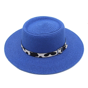 Detail of blue straw hat featuring cow print ribbon and silver metal buckle decoration