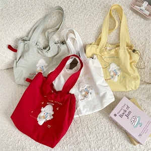 Flat lay of four colorful canvas tote bags featuring cute cartoon dog embroidery and drawstrings