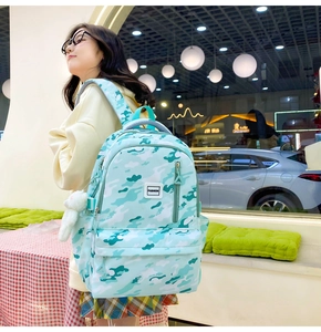 Close-up of green camo backpack with fashion label and white bunny plush charm