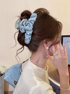 Detailed view of light blue heart-pattern scrunchie paired with a glitter hair claw clip
