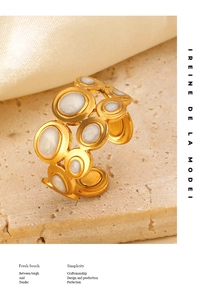 Artistic detail of a gold-plated geometric ring featuring circular mother-of-pearl inlays