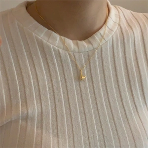 Minimalist gold-plated irregular V-shaped necklace worn by a model over a white sweater
