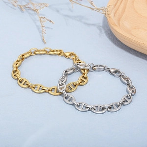 Gold and silver stainless steel pig nose chain bracelets with lobster clasp on blue surface