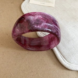 Detailed macro view of high-gloss resin bangle with purple and white marble texture