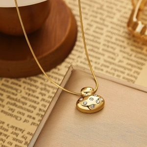 Macro detail of gold irregular heart pendant with white crystals on vintage newspaper