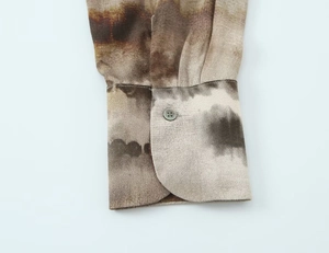 Close-up of sleeve cuff with brown gradient tie-dye pattern and round button detail