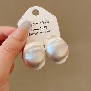 Dettaglio degli orecchini a perno ovali in metallo spazzolato argento stile minimalista.