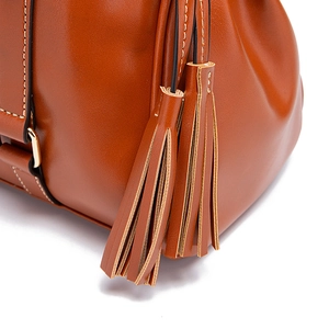 Primer plano de bolso de cuero marrón retro con borlas dobles y costuras blancas