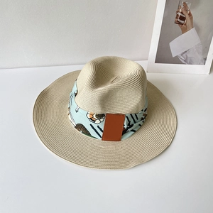 Vue détaillée d'un chapeau de paille beige avec ruban floral bleu et écusson en cuir