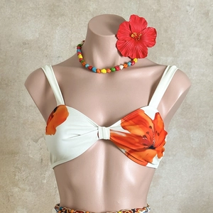 Detail of white bikini top with orange floral print and front bow tie design