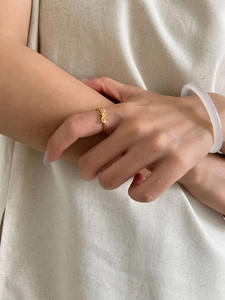 Close-up of golden bow-shaped open ring with cubic zirconia stones on model's finger