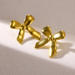 Macro detail of geometric matte gold bow earrings with luxury brushed metal texture