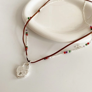 Detail view of double-layer leather necklace with heart lock pendant and colored beads