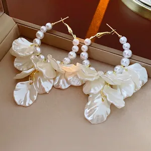 Elegant gold earrings with iridescent floral petals and pearls in a luxury display case