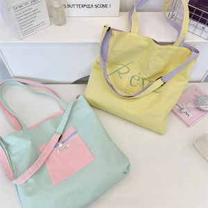 Detail of Rêve embroidery on high-capacity contrast color nylon tote bags in soft pastels