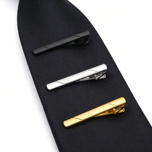 Close-up of three classic men's stainless steel tie clips in gold, silver, and black finish