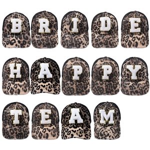 Close-up of distressed leopard print trucker hats with sequin patch letters and mesh back