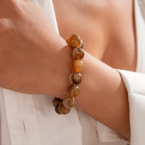 Detailed shot of amber resin beaded bracelet showing natural swirl textures on skin