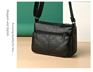 Close-up of black leather crossbody bag with litchi texture and V-shaped stitching detail