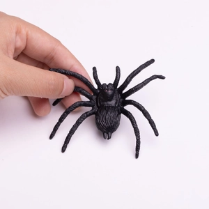 Realistic black spider prank toy held in hand featuring detailed furry texture