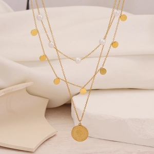Layered gold chain necklace with pearls and Elizabeth II coin pendant on white fabric