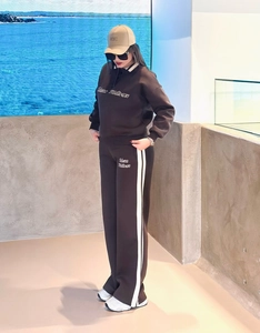 Detail of dark brown polo sweatshirt with white side stripe sweatpants and NYC cap