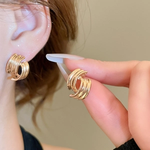 Detailed view of layered golden twisted geometric earrings with a polished metallic finish