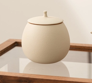 Macro view of beige ceramic tea canister with matte texture and round spherical shape