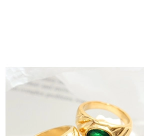 Detailed macro view of textured gold-plated earrings with emerald green gemstones