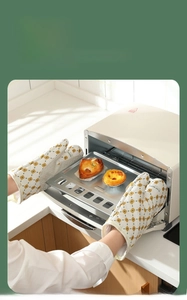 Thickened oven mitts protecting hands while taking hot baking tray out of a modern oven
