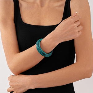 Macro detail of dark green acrylic bangle with vertical spiral texture on a wrist