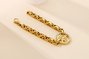 Macro view of gold Hamsa hand charm on a Byzantine chain with sparkling zircon stones