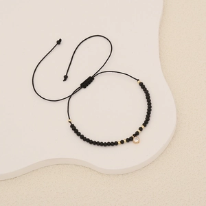 Close-up of black beaded bracelet with gold accents and a crystal zircon pendant
