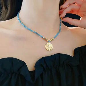 Ethnic beaded necklace with blue evil eye pendant and gold accents on a female model