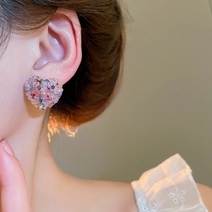 Close-up of pink heart-shaped stud earrings with sparkling colorful glitters on model