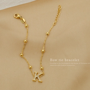 Elegant gold titanium steel bracelet with letter K zircon pendant on textured background