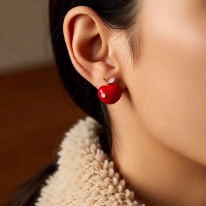 Close-up of a red cherry pendant earring with zircon-inlaid leaf on a female model