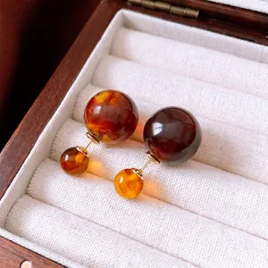 Retro amber-textured resin double bead earrings in gold-plated finish on a jewelry box