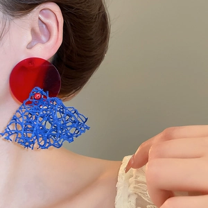 Gros plan détaillé de boucles d'oreilles rétro en résine rouge et bleu roi sur l'oreille
