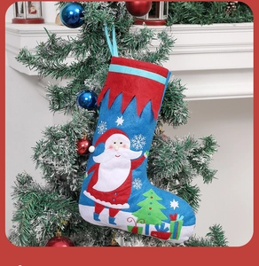 Blue Christmas stocking with Santa applique hanging on a snow-decorated tree branch