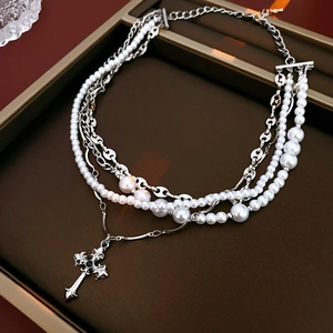 Detail showing multi-layer silver chain with white pearls and black stone cross pendant