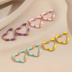 Minimalist stainless steel heart hoop earrings in multiple colors on beige fabric