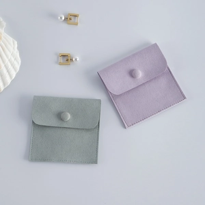 Detail view of velvet jewelry pouches in sage green and lavender with snap button closure