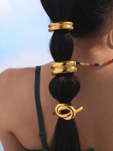 Close-up of golden metal ponytail cuffs and twisted hair rings on a model hairstyle
