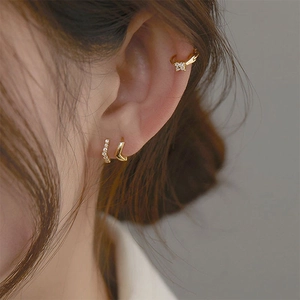 Detailed close-up of gold ear cuff set with white zircons on a model ear